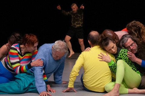 People in colorful suits sit on the stage floor