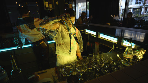 Person hinter einer Bar schenkt ein Getränk ein