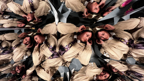 Person liegt inmittien von zahlreichen Spiegeln, die ihr Spiegelbild zeigen