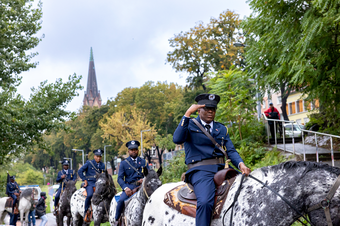 Vier Ovaherero sitzen in blauen Uniformen auf Pferden
