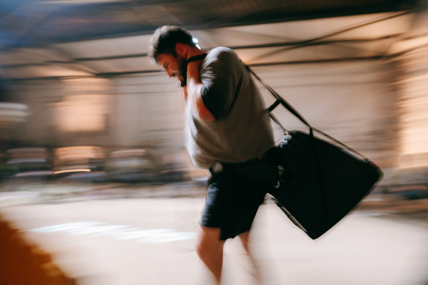 Eine Person läuft durch einen hell erleuchteten Raum, auf dem Rücken trägt sie einen alten Röhrenfernseher