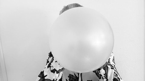 Person blows into a balloon. The face cannot be seen