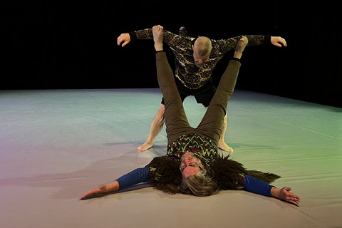 Auf dem Boden liegende Person stützt eine andere mit den Füßen