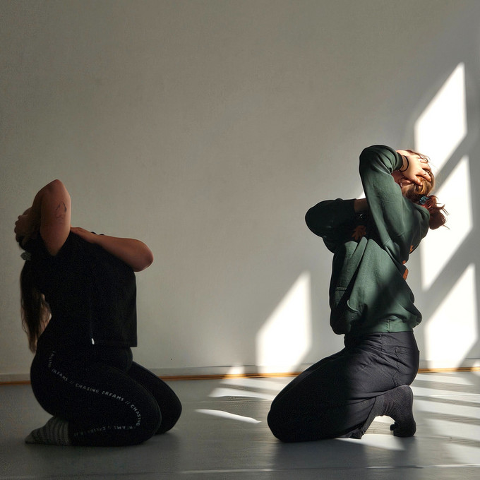 Zwei Personen knien sich gegenüber auf dem Boden und halten ihre Köpfe