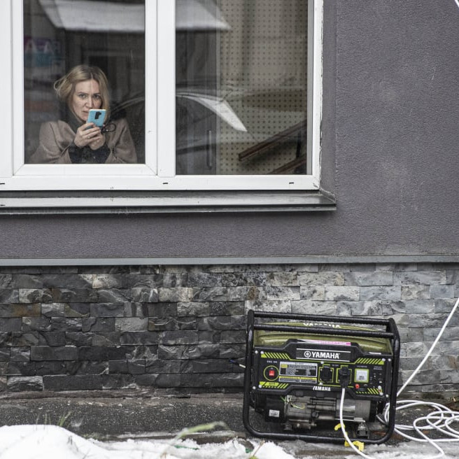 Person macht ein Foto aus einem Fensert auf die Straße. Dort steht ein Generator.