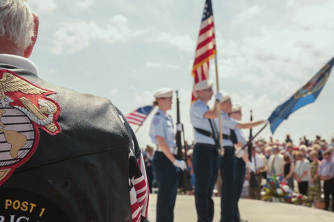 Soldaten mit einer Flagge stehen umgeben von Menschen