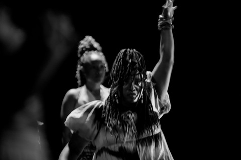 schwarz-weiß Foto von zwei Personen, die Person im Vordergrund streckt den Arm in die Höhe