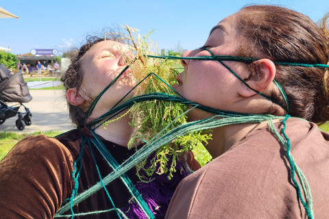 Zwei Frauen, die durch Wolle miteinander verschnürt sind.