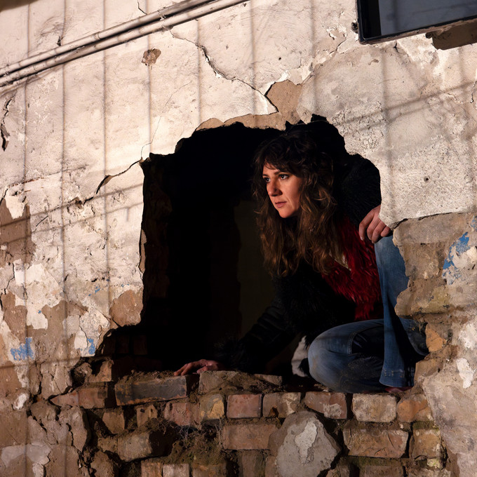 Person schaut aus einem Loch in der Mauer.