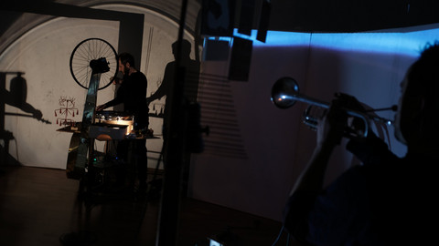 Band steht verteilt in einem Raum und spielt Musik