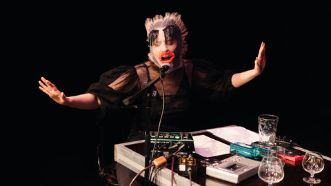 Person mit Maske singt in ein Mikrofon