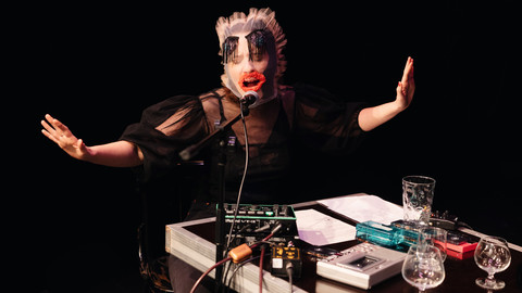 Person mit Maske singt in ein Mikrofon