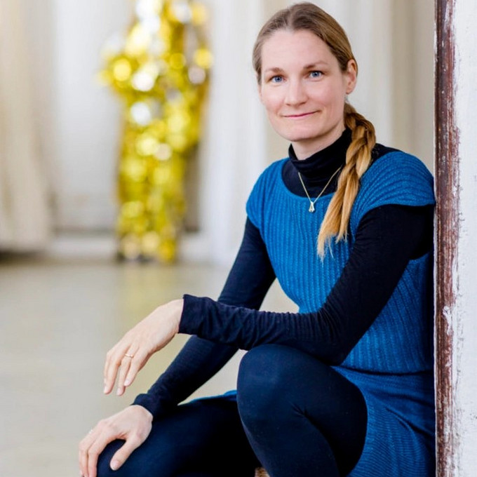 Person sitzt in der Hocker auf dem Boden und blickt in die Kamera