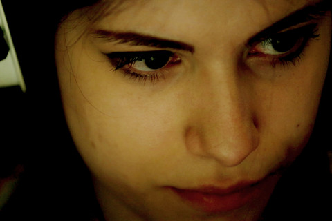 Weiße Frau mit Kopfhörer schaut zur Seite. Ihr Gesicht wird von gelblichem Licht erhellt.