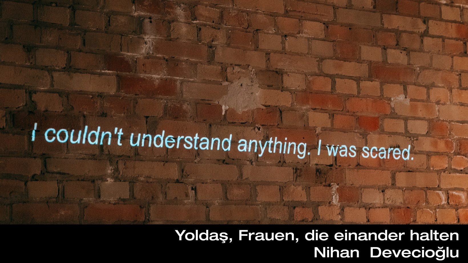 Backsteinmauer auf die der Satz "I couldn´t understand anything. I was scared" projiziert ist