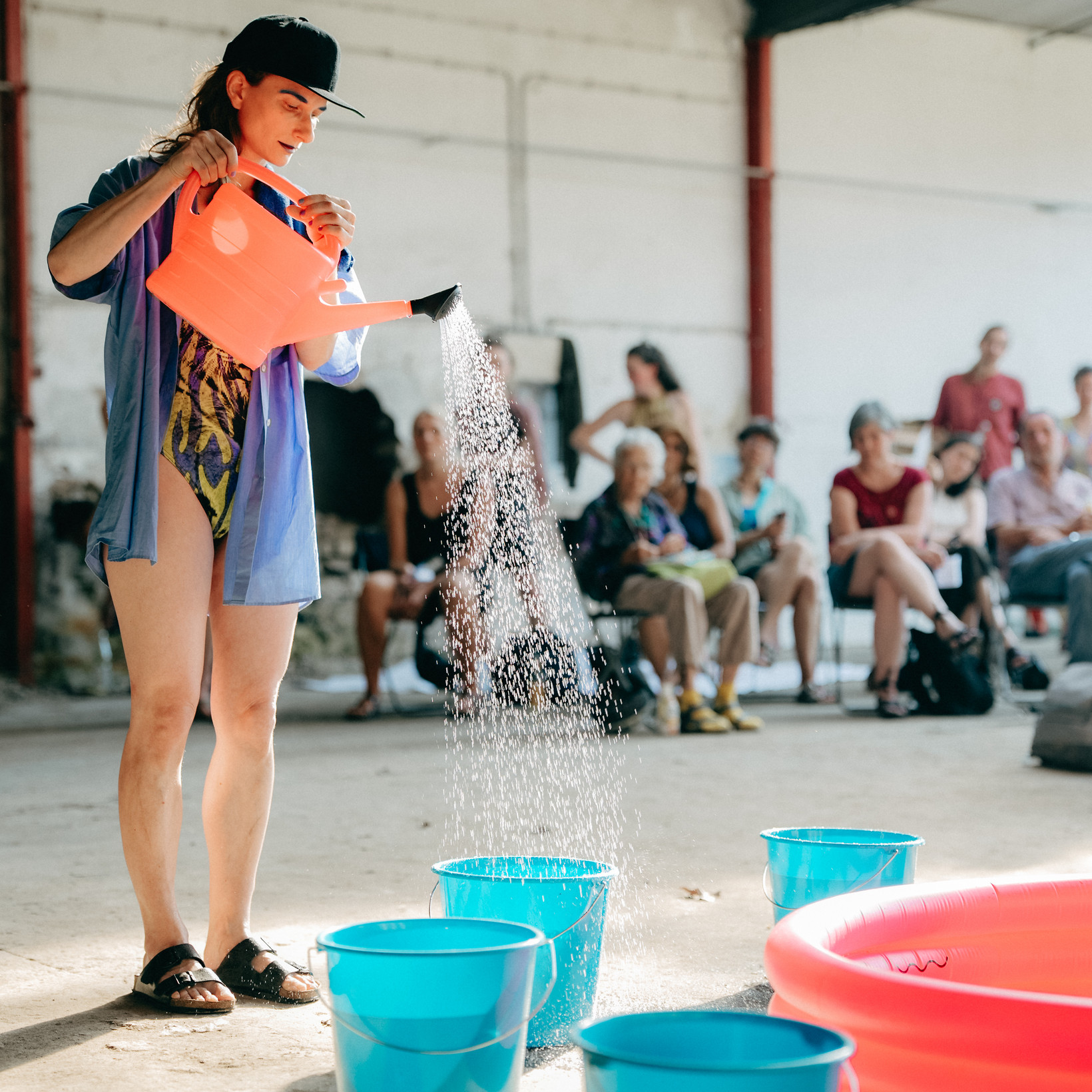 Person schüttet mit einer Gießkanne Wasser in Eimer