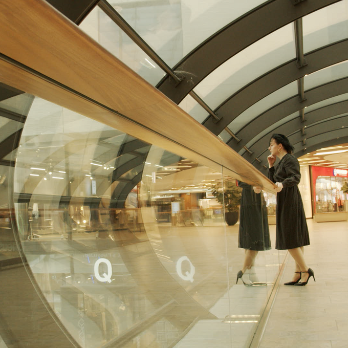 Person in black dress standing in a glass passage way
