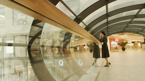 Person im schwarzen Kleid steht in einem Glas-Übergang
