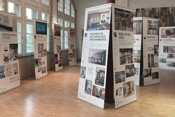 Ausstellungsraum mit zahlreichen Roll-Up Displays die unterschiedliche Bilder und Texte zu Innenarchitektur enthalten