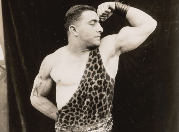 Historisches Sepia Foto eines Mannes in Leofell, der seine Muskeln zeigt.