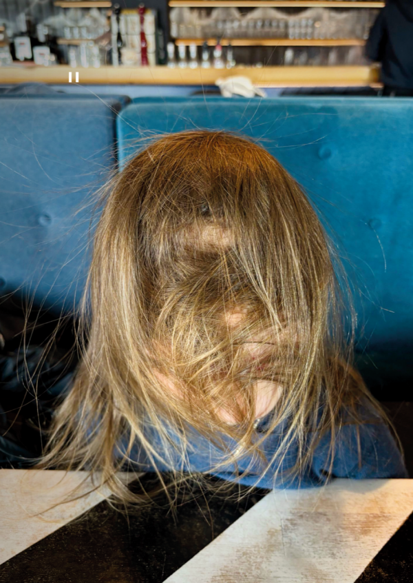 Eine Person mit ganz viel Haaren im Gesicht sitzt am Tisch.